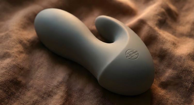 Primo piano macro di un accessorio tecnologico Eros Atelier in silicone grigio vellutato con incisione Certified Platinum Silicone su tessuto di lino caldo